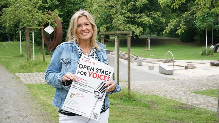 Kulturbeauftragte zeigt das Plakat der Veranstaltung 