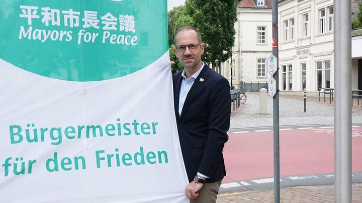 Bürgermeister Ansgar Mertens hisst Flagge für den Frieden auf dem Rathausvorplatz
